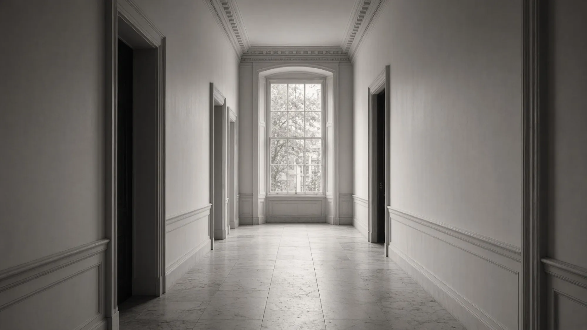 A long empty townhouse hallway ending in a tall window.