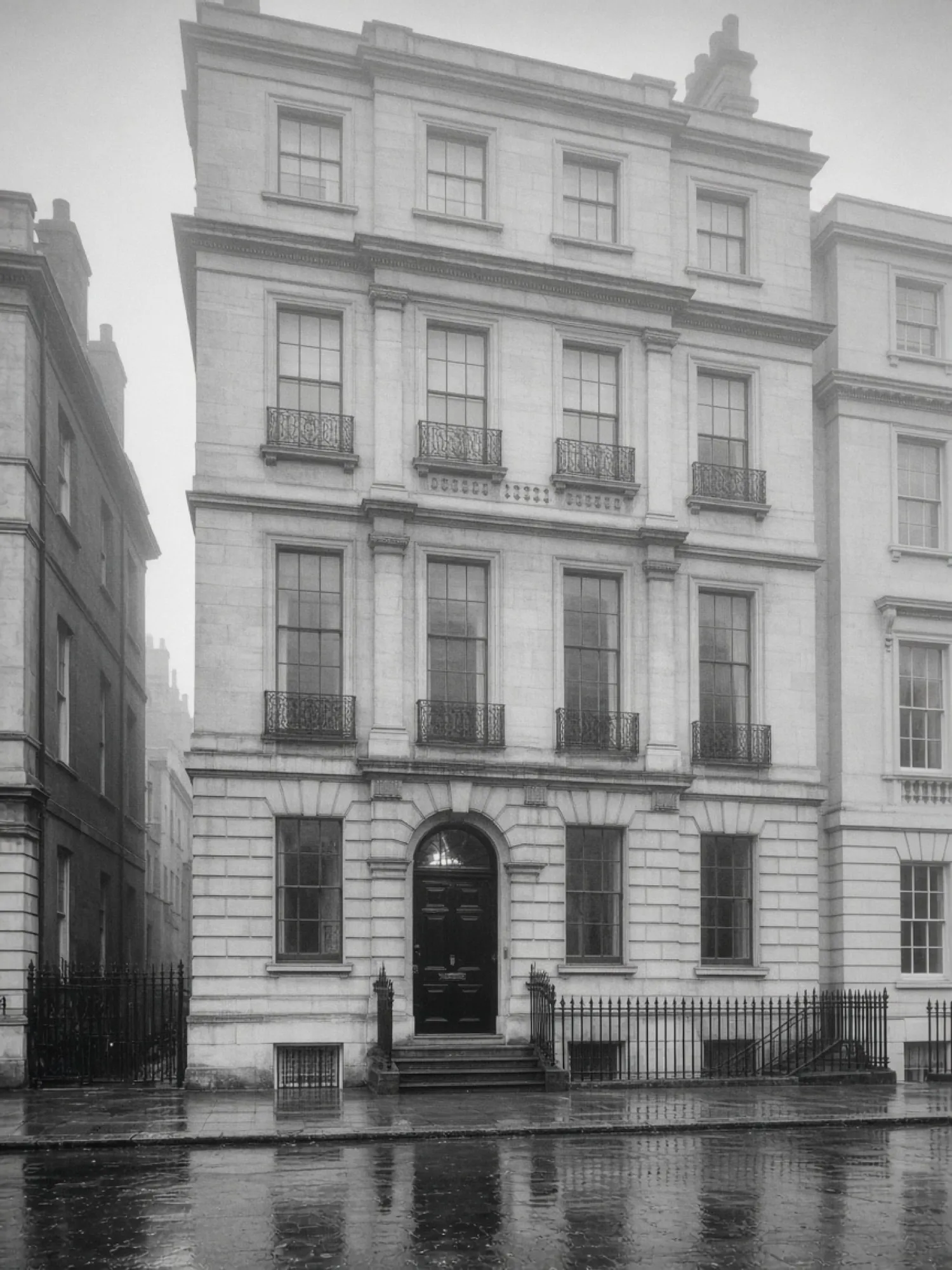 A pale stone townhouse on a wet London street, photographed in fog.